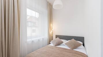 A neatly made bed with a patterned bedspread, a grey headboard, and two pillows.