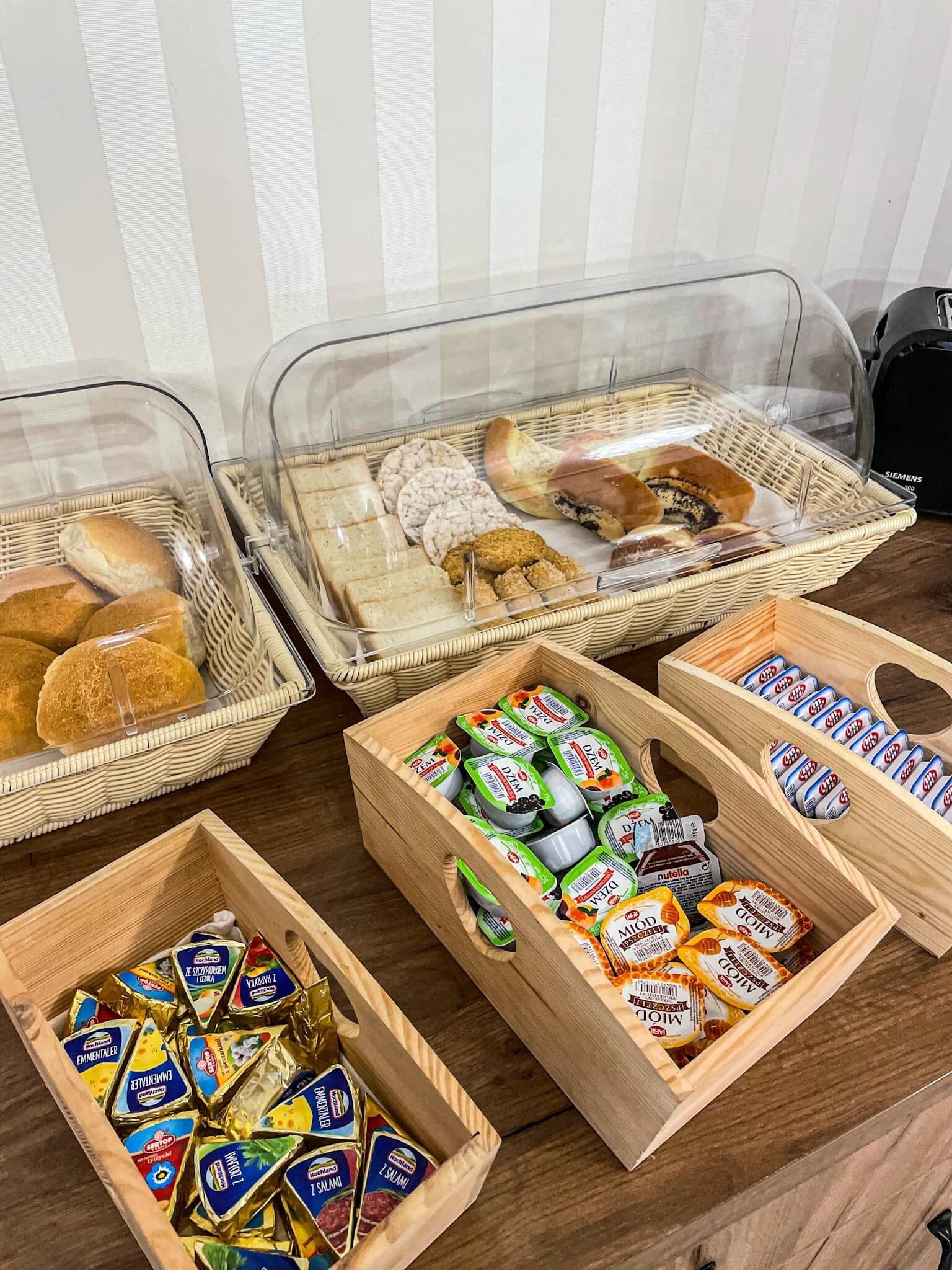 A buffet with various food items including bread, pastries, and packaged snacks.