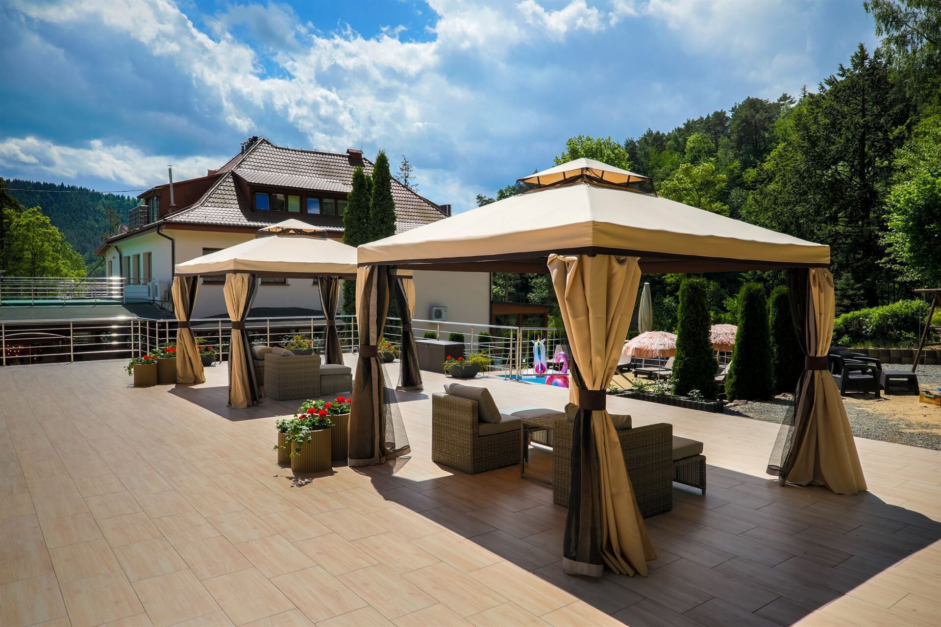 A covered outdoor seating area with wicker furniture and a pool in the background.