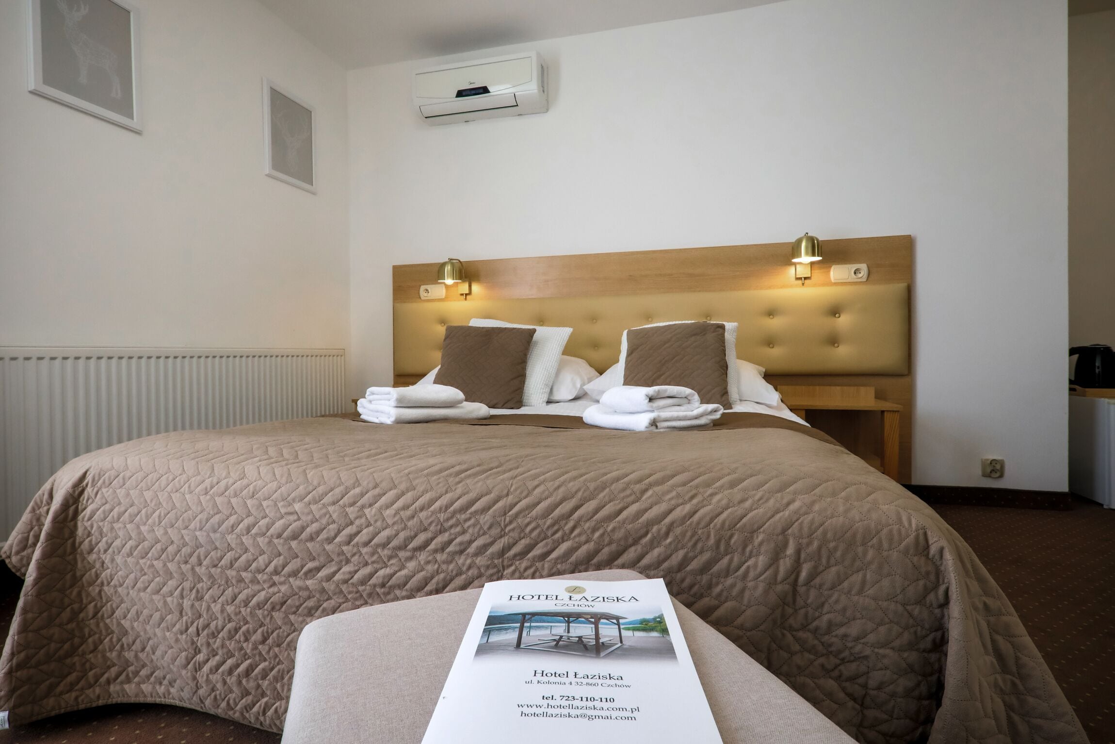 A hotel room with a large bed, two bedside lamps, a headboard, and a brochure on the bed.