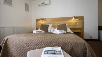 A hotel room with a large bed, two bedside lamps, a headboard, and a brochure on the bed.