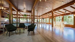 A spacious indoor area with wooden beams, large windows, and modern furniture. - Hotel Łaziska (Czchow)