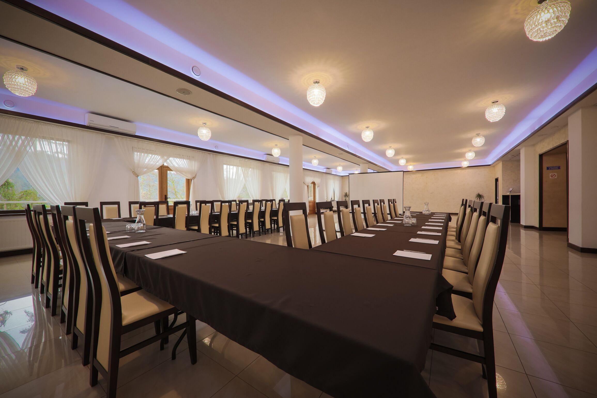A conference room with a long table, chairs, and chandeliers.