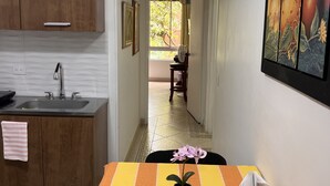 A kitchen with wooden cabinets, a sink, and a striped tablecloth with a potted orchid.