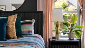 A bedroom with a bed, pillows, a bedside table with a lamp, and a potted plant. - Botany House Designer Home with Hot Tub (Santa Rosa)