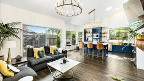 A spacious living area with a sofa, coffee table, and a kitchen area with bar stools. - Botany House Designer Home with Hot Tub (Santa Rosa)