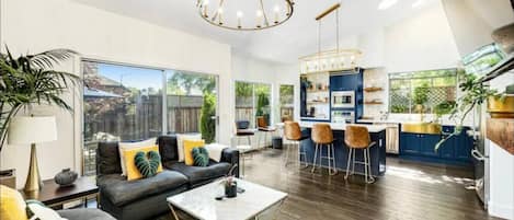 A spacious living area with a sofa, coffee table, and a kitchen area with bar stools.