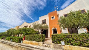 A building with a red and beige facade, a staircase leading to the entrance, and a clear blue sky. - Stagnone Wine House (Marsala)