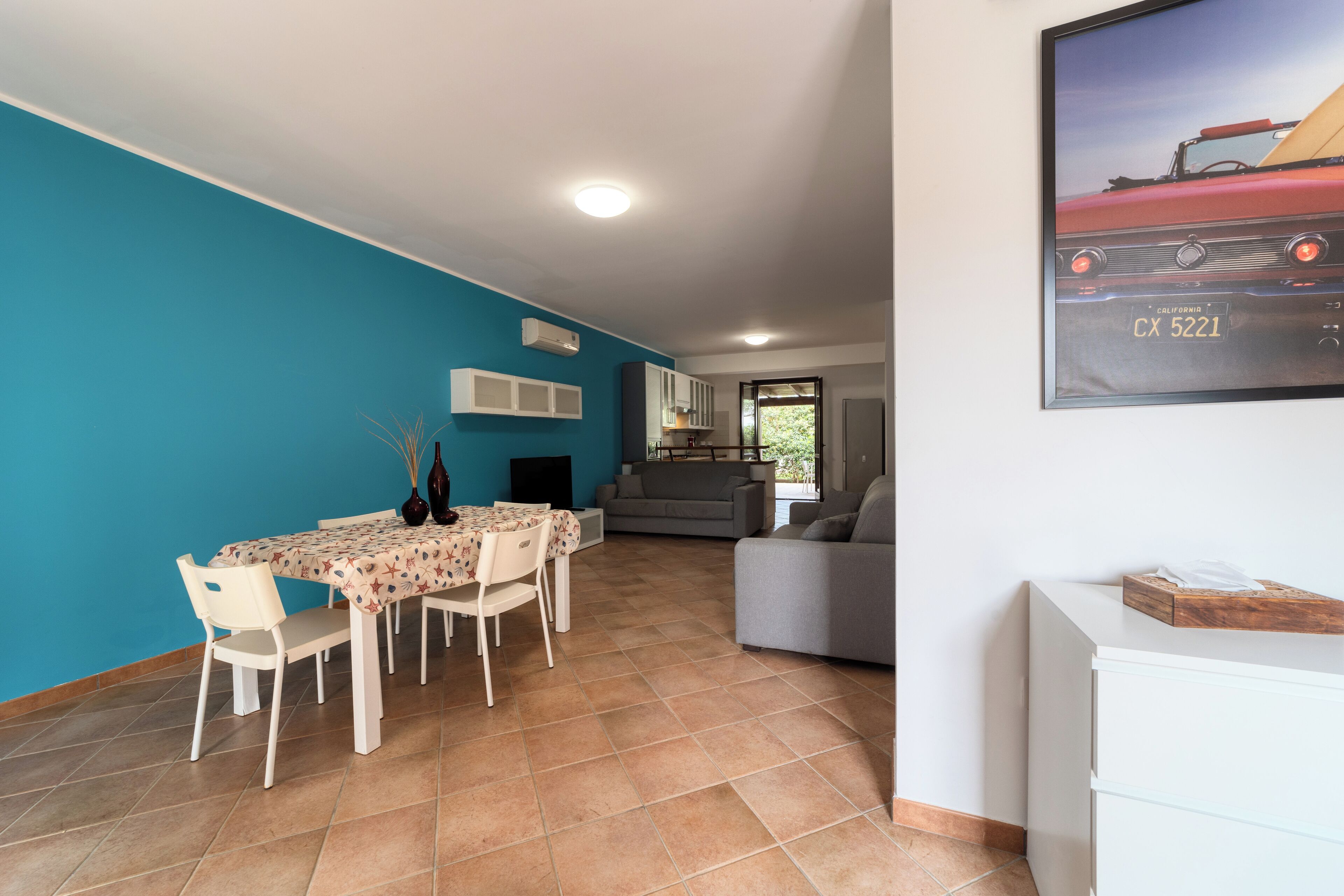 A dining area with a table and chairs, a sofa, and a TV in the background.