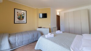 A bedroom with a bed, a sofa, a television mounted on the wall, and a framed picture on the wall. - Stagnone Wine House (Marsala)