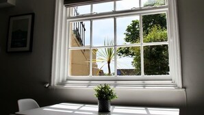 A room with a large window, a table, and chairs. - Molokai Snug | Best location | North South bay | Courtyard garden | Parking (North Yorkshire)
