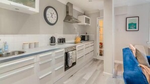 A modern kitchen with white cabinets, a stainless steel sink, and a built-in oven. - Molokai Snug | Best location | North South bay | Courtyard garden | Parking (North Yorkshire)