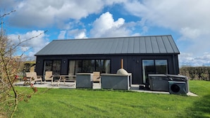 Et moderne hus med stor terrasse, udendørs møbler og et stort vindue.