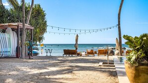 A beachside lounge with surfboards, wooden chairs, and umbrellas, overlooking the ocean.