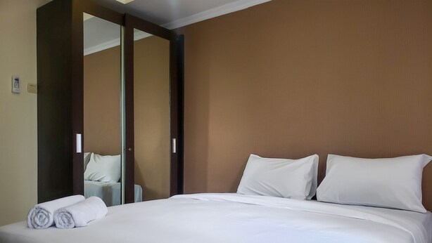 Une chambre d’hôtel avec un grand lit, du linge de lit blanc et un miroir au mur.