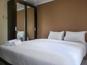 A hotel room with a large bed, white linens, and a mirror on the wall. - Elegant And Comfy Studio Apartment Belmont Residence Puri (Jakarta)