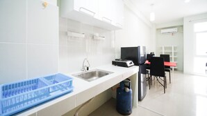 Une cuisine moderne équipée d’un évier, d’un récipient en plastique bleu, d’une bouteille de gaz et d’un coin repas avec des chaises et une table.
