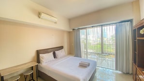 A hotel room with a bed, a desk, two chairs, an air conditioning unit, and a balcony with a view. - Cozy Stay Studio At Ambassade Kuningan Apartment (Jakarta)