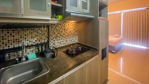 A compact kitchen with a sink, stove, and cabinets. - Cozy Stay Studio At Ambassade Kuningan Apartment (Jakarta)