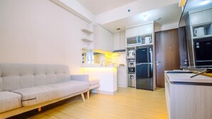 Eine moderne Küche mit integrierten Geräten, einem grauen Sofa und einem Holzes Esstisch.