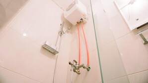 A bathroom with a shower, a white toilet, and a wall-mounted heater. - Simply Look Studio At Amazana Serpong Apartment (South Tangerang)
