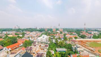 Paisagem urbana com mistura de edifícios residenciais e comerciais, incluindo uma torre imponente e um grande campo aberto.