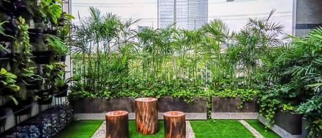 Un jardin sur le toit, agrémenté de gazon synthétique, de jardinières en bois et de différentes espèces de plantes vertes.