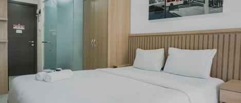 A hotel room with a large bed, a wooden wardrobe, a glass shower enclosure, and a cityscape painting on the wall.