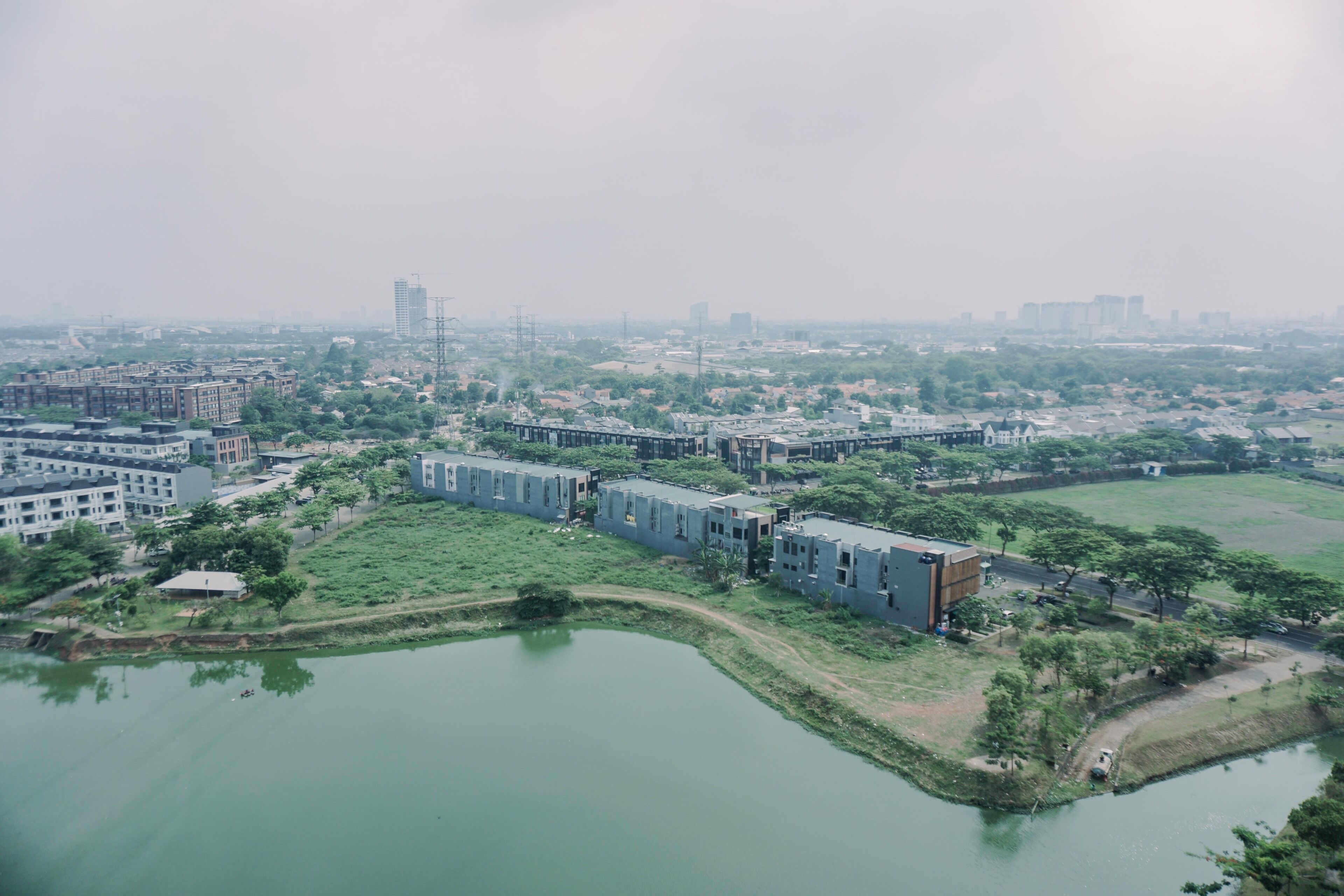 An aerial view of a residential area with buildings, a river, and greenery.
