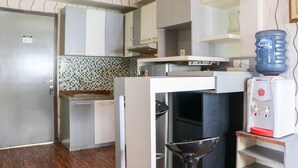 Una cocina compacta con microondas, dispensador de agua y lavamanos.