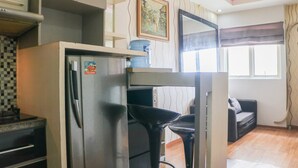 Un espacio habitable pequeño con kitchenette, un sofá y zona de comedor.