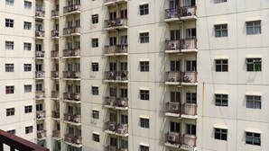 Un edificio residencial de varios pisos con balcones y unidades de aire acondicionado.