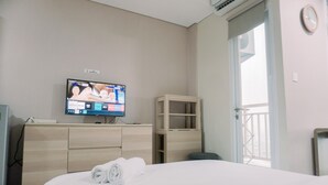 A hotel room with a bed, a TV on the wall, a wooden dresser, and a balcony door.