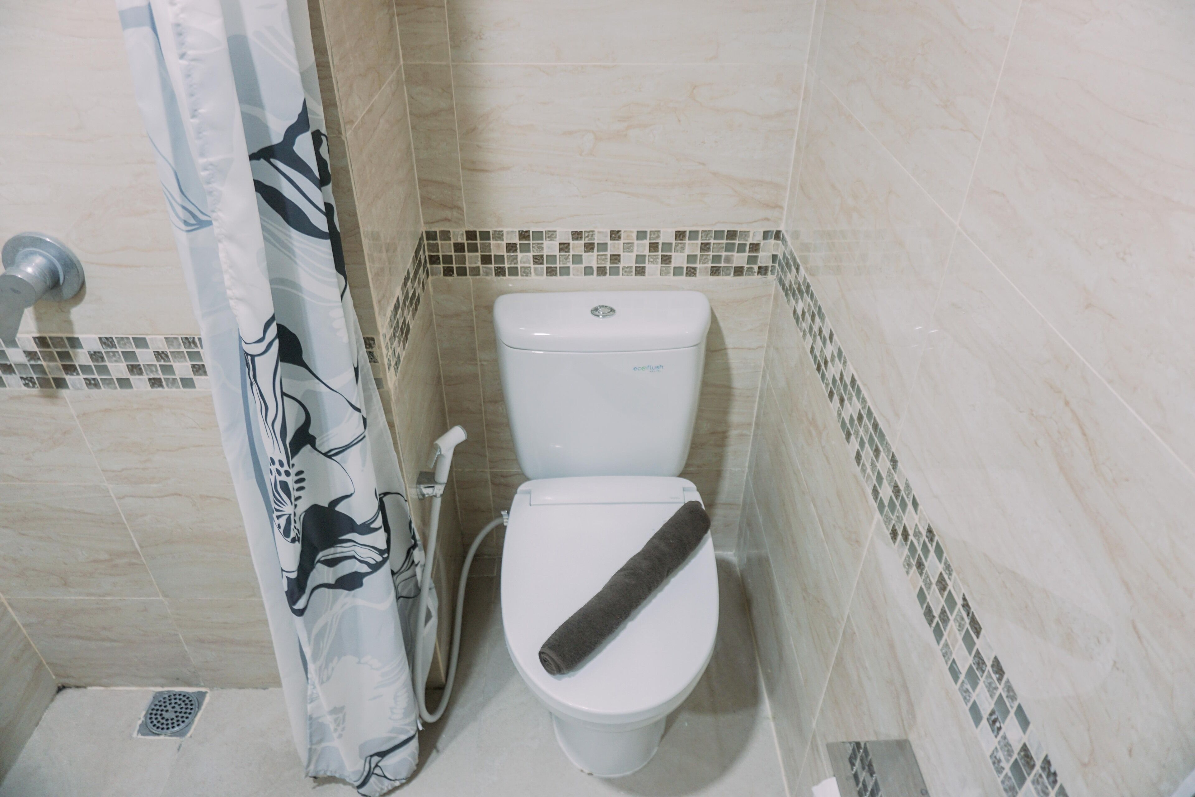 A bathroom with a toilet, shower curtain, and tiled walls.