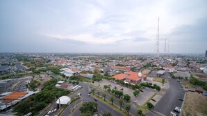 A cityscape with a prominent tower, residential buildings, and a large open area with parked vehicles. - Modern And Homey Studio At Tanglin Supermall Mansion Apartment (Surabaya)