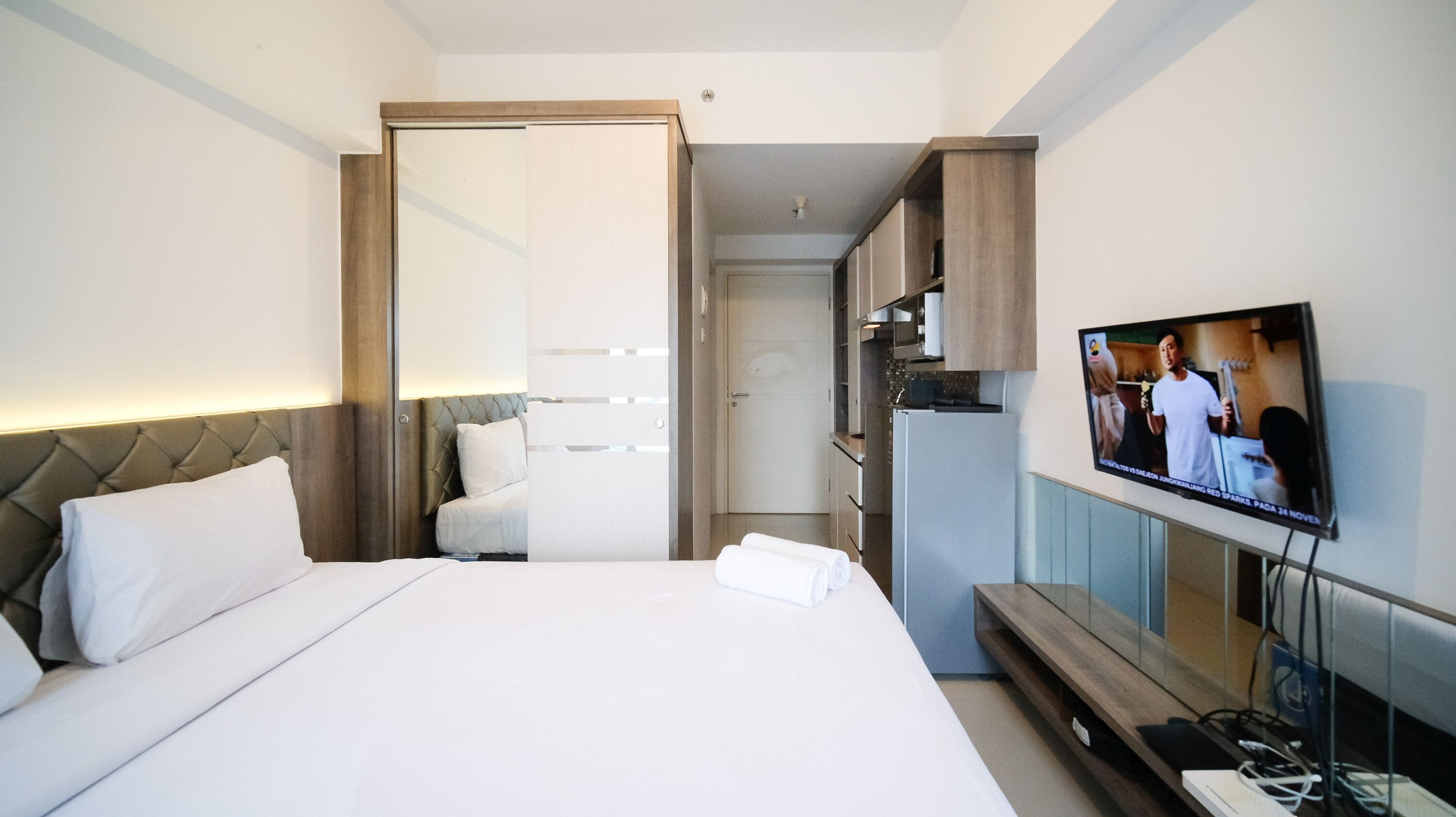 Ein Hotelzimmer mit Bett, Fernseher und Küchenzeile.