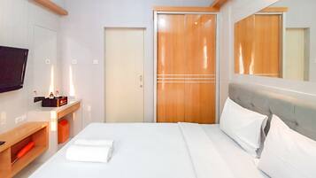 Ein Hotelzimmer mit Bett, Fernseher, Holzschrank und Spiegel.
