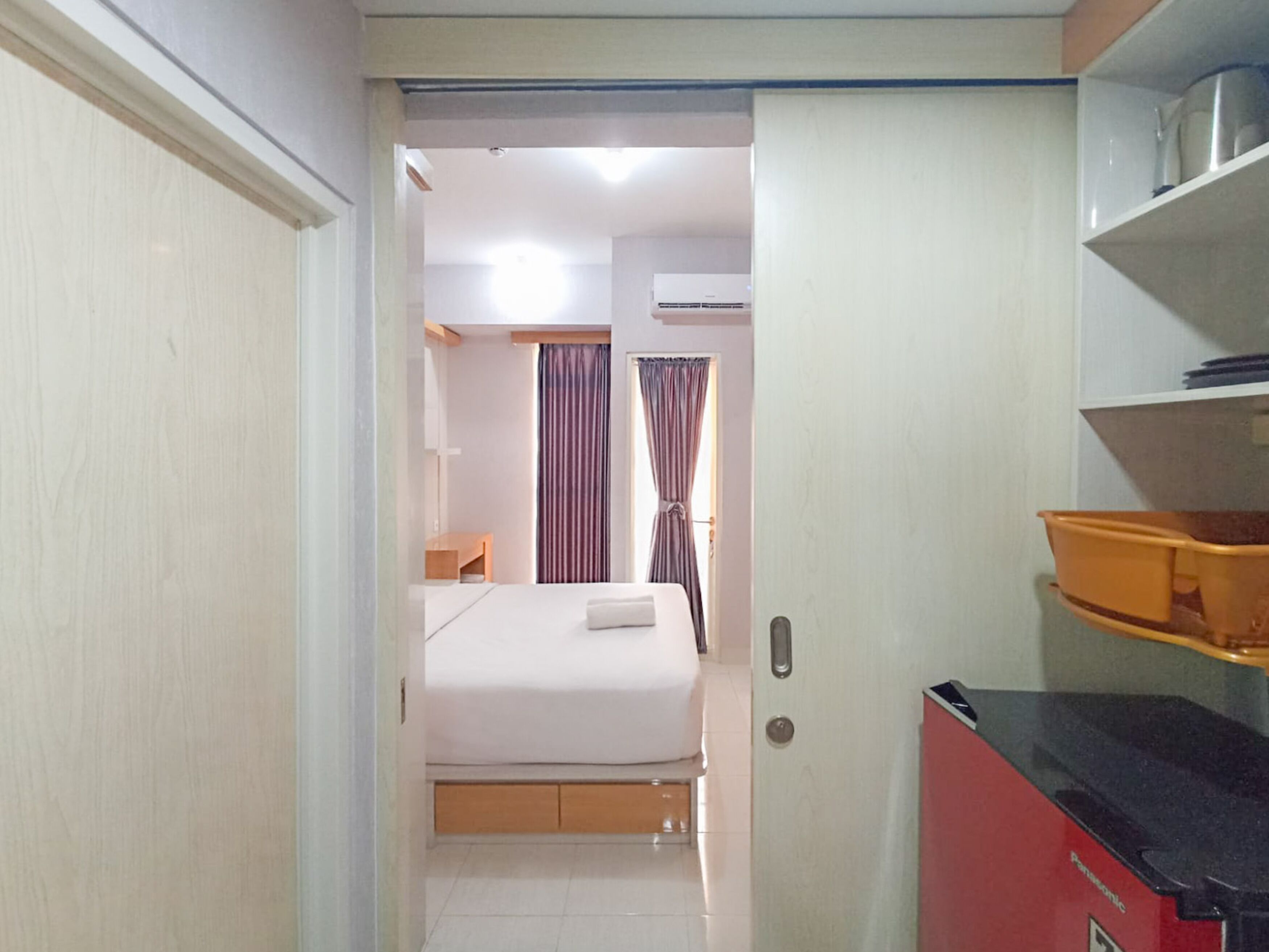A hotel room with a bed, a desk, and a kitchenette.
