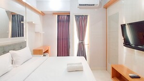 Una habitación de hotel moderna con una cama grande, televisión, escritorio y ventana con cortinas.