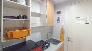 Una cocina compacta con armarios blancos, encimera negra, un lavabo y una licuadora Panasonic.