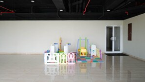 Une pièce spacieuse et vide, dotée d’un plancher ciré, d’une porte et d’équipements de jeu colorés.