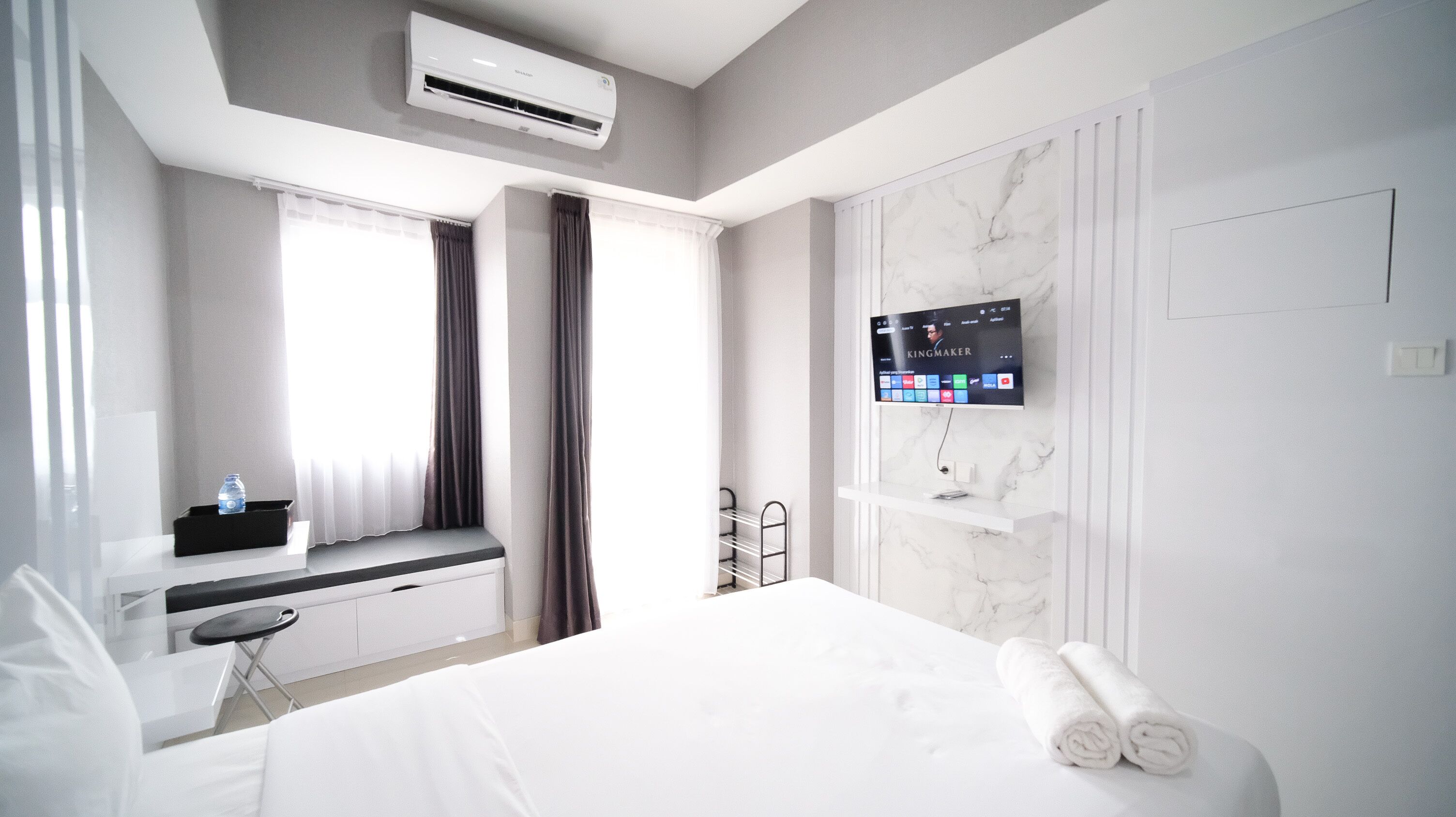 Habitació d'hotel amb un llit, una taula de treball amb una cadira, un televisor fixat a la paret i un aparell d'aire condicionat.
