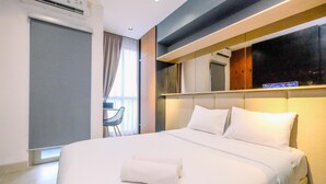 Ein Hotelzimmer mit einem großen Bett, einem Nachttisch, einem Sessel und einem Fenster mit Vorhängen.