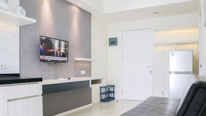 A modern kitchen with a flat-screen TV, white cabinets, and a black countertop. - Simply 2Br Apartment At Parahyangan Residence (Bandung)