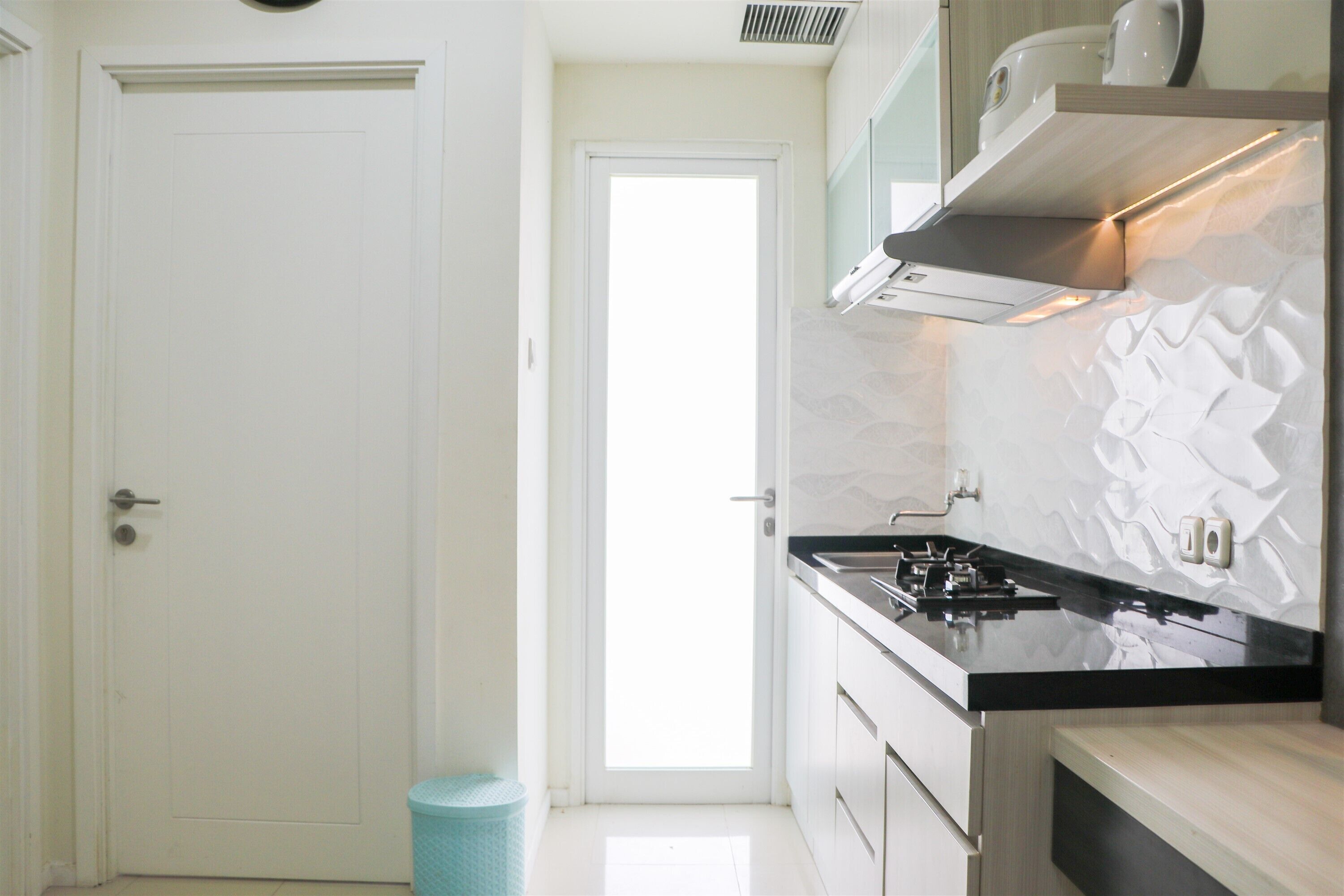 Une cuisine moderne avec des meubles blancs, un plan de travail noir et une hotte en acier inoxydable.