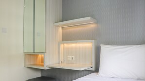 A hotel room with a bed, a small bedside table, and a wall-mounted shelf with a mirror and light. - Simply 2Br Apartment At Parahyangan Residence (Bandung)