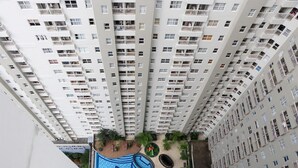 A high-rise residential building with multiple balconies and a swimming pool area. - Simply 2Br Apartment At Parahyangan Residence (Bandung)