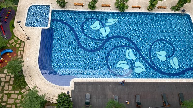 An aerial view of a swimming pool with a mosaic design, surrounded by a paved walkway and benches. - Good Choice And Homey 2Br At Signature Park Grande Apartment (Jakarta)