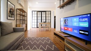 Una sala de estar moderna con un televisor de pantalla plana, un sofá gris, una mesa de centro de madera y una alfombra estampada.