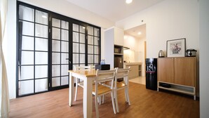 Un espacio habitable compacto con comedor, kitchenette y puerta corrediza que da a un balcón.